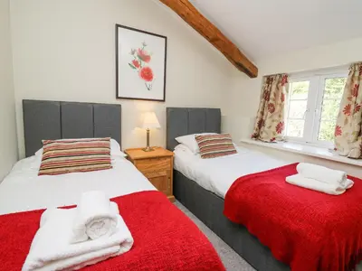 two beds in a bedroom with red and white sheets at Penuwch Fach in Llanfihangel-y-creuddyn