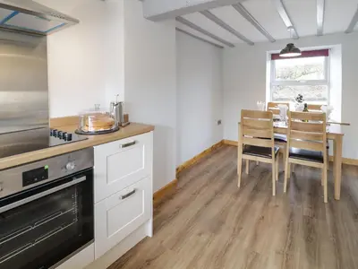 a kitchen with white cabinets and a table with chairs at Bryndan in Machynlleth