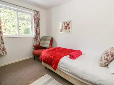 a bedroom with a bed and a chair and a window at Dolau Meurig in Ystrad Meurig