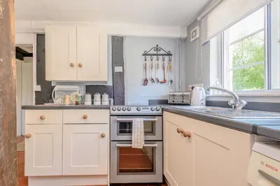 a kitchen with white cabinets and a stove top oven at Fern Hall Cottage in Upper Welson