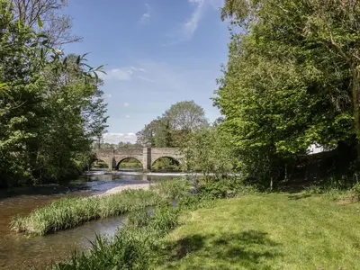 a river with a bridge in the background at Fern House in Craven Arms
