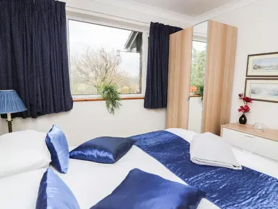 a bedroom with a bed with blue pillows and a window at Blaenywawr Annexe in Cross Inn