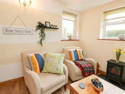 a living room with two chairs and a table at Blaenywawr Annexe in Cross Inn