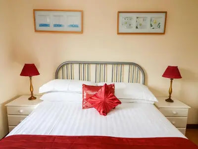 a bedroom with a white bed with a red bow on it at Blaenywawr in Cross Inn