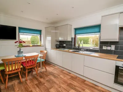 a kitchen with a table and chairs and a dining room at Blaenywawr in Cross Inn