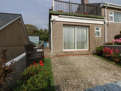 a house with a bench and a balcony at Maesawel Studio in Harlech