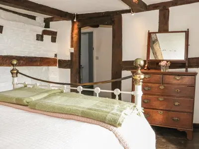 a bedroom with a bed and a dresser and a mirror at Lower Hodre in Bucknell