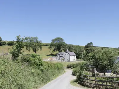 a road leading to a white house on a hill at Lower Hodre in Bucknell