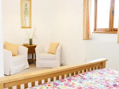 a bedroom with two chairs and a bed at Acorn Cottage 1 in Petton