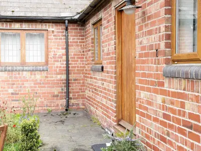 a brick building with a wooden door and windows at Acorn Cottage 1 in Petton