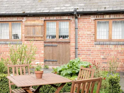 a wooden table and chairs in front of a brick building at Acorn Cottage 1 in Petton