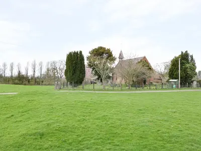 a field of grass with a church in the background at Acorn Cottage 1 in Petton