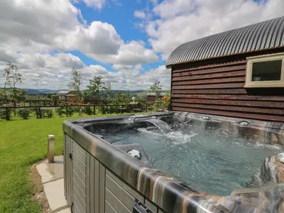 a hot tub in the backyard of a house at Woodland View in Saint Harmon