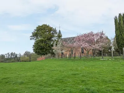a church in a field with a tree in front of it at Acorn Cottage 2 in Petton