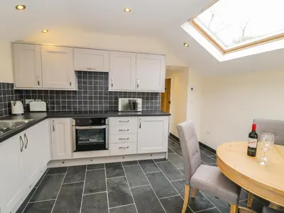 a kitchen with white cabinets and a table at Bothi in Bala