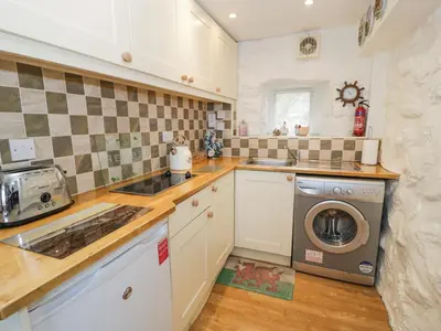 a kitchen with a sink and a washing machine at Happy Landing in Harlech