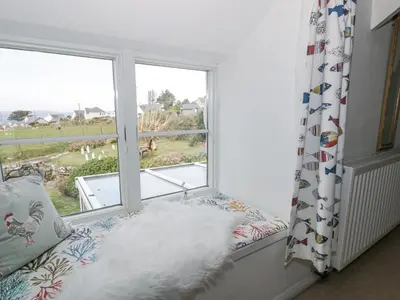 a window seat with a white pillow and a window with a view at Happy Landing in Harlech