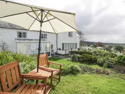 a wooden bench with an umbrella in the yard of a house at Happy Landing in Harlech