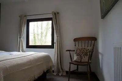 a bedroom with a bed and a chair and a window at Arrowwood Self Catering (Wagtail and Nuthatch) in Kington