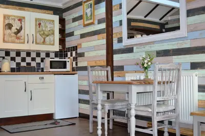 a kitchen with a table and chairs and a wooden wall at Arrowwood Self Catering (Wagtail and Nuthatch) in Kington