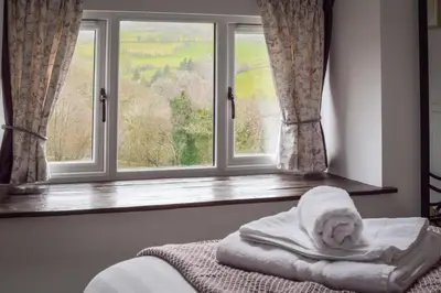 a bed in front of a window with a pile of towels at 2 Bed in Machynlleth oc-bow39 in Darowen