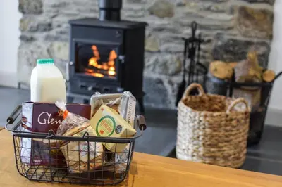 a basket of food and milk on a table with a fireplace at 2 Bed in Machynlleth oc-bow39 in Darowen