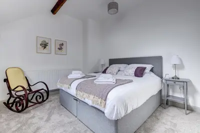 a bedroom with a large bed and a chair at 5 Bed in Machynlleth oc-bow30 in Darowen
