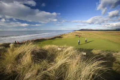 two people playing golf on a golf course next to the ocean at 5 Bed in Machynlleth oc-bow30 in Darowen
