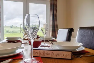 a wooden table with wine glasses and plates on it at 3 Bed in Bala oc-bow26 in Llanuwchllyn