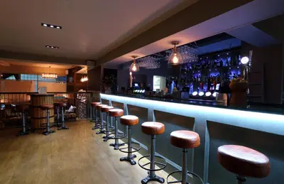 a bar with a row of stools in a room at The Loopy Shrew in Shrewsbury