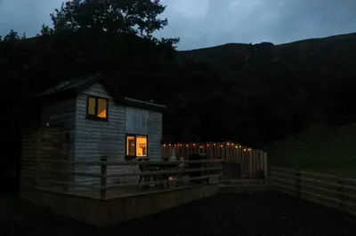 a small cabin with lights in the window at night at Nant Cafn - Hafan Hideaways Eryri in Machynlleth