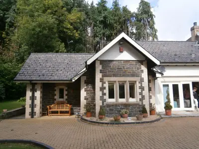 a brick house with a bench in front of it at Plas Y Dderwen Apartments in Aberystwyth