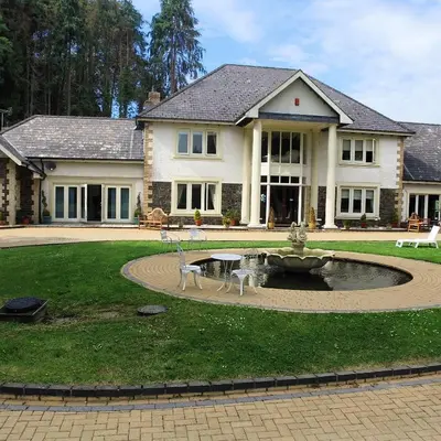 a house with a fountain in the middle of a yard at Plas Y Dderwen Apartments in Aberystwyth