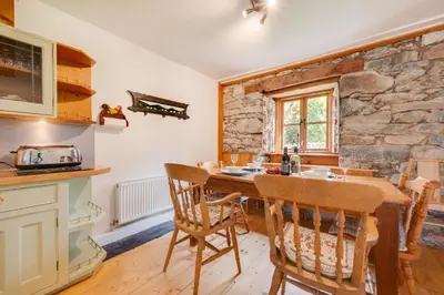 a kitchen with a table and chairs and a stone wall at 3 Bed in Dolgellau oc-wah569 in Llanfachreth