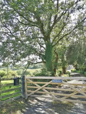 a wooden gate with a sign on it next to a tree at 3 Bed in Llangadfan oc-wae284 in Llangadfan