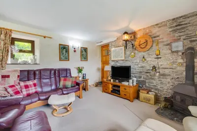 a living room with a purple couch and a stone wall at Bryncylla in Llangurig