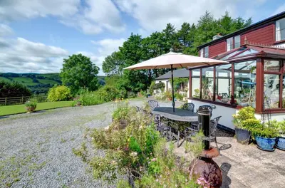 a patio with a table and an umbrella at Bryncylla in Llangurig