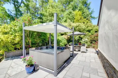 an outdoor hot tub with an umbrella on a patio at Bryncylla in Llangurig