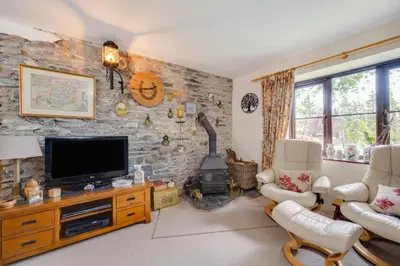 a living room with a tv and a stone wall at Bryncylla in Llangurig