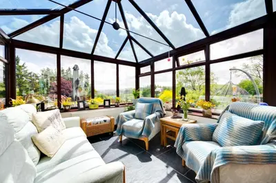 a conservatory with two chairs and a couch and windows at Bryncylla in Llangurig