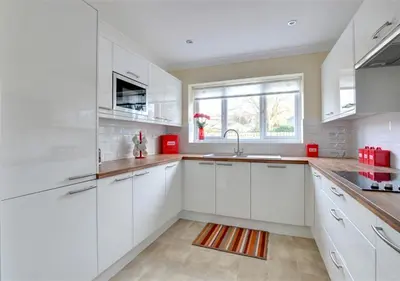 a white kitchen with white cabinets and a window at Tredegar in Dyffryn