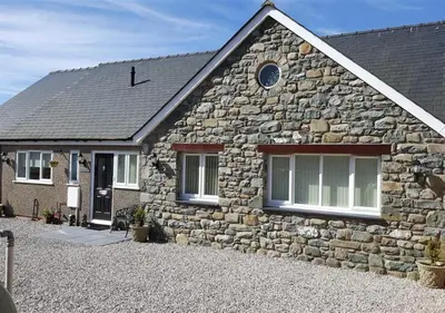 a stone house with a stone wall at Tredegar in Dyffryn
