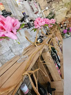 a table with a vase with pink flowers and wine bottles at The Beacons Guest House in Brecon
