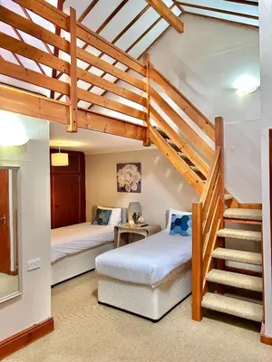 a bedroom with two beds and a staircase in a house at The Beacons Guest House in Brecon