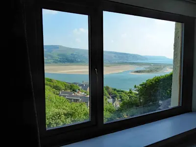 a window with a view of a beach and the ocean at Bryn Melyn Apartments in Barmouth