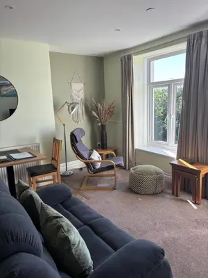 a living room with a blue couch and a window at Bryn Melyn Apartments in Barmouth