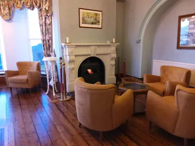 a living room with chairs and a fireplace at Tyr Graig Castle in Barmouth