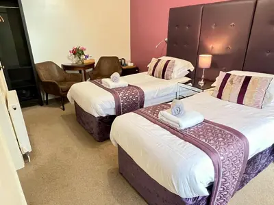 a hotel room with two beds and a table at Dolgun Uchaf Historic B&B and Cottages with Boutique Bedrooms In The Heart of Snowdonia in Dolgellau