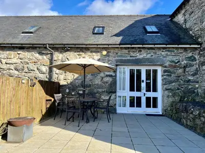 a table with an umbrella in front of a stone building at Dolgun Uchaf Historic B&B and Cottages with Boutique Bedrooms In The Heart of Snowdonia in Dolgellau