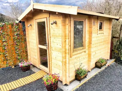 a wooden shed with potted plants and a fence at Dolgun Uchaf Historic B&B and Cottages with Boutique Bedrooms In The Heart of Snowdonia in Dolgellau